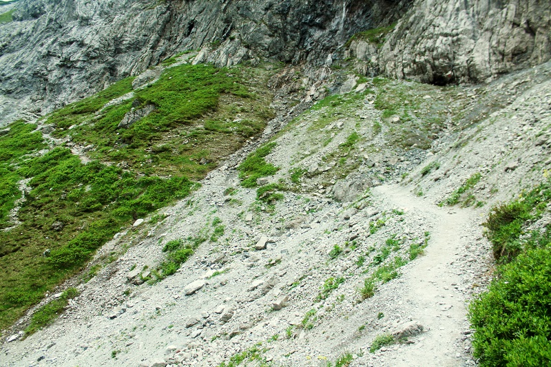 Chodník vedie suťovým terénom popri skalnej stene...